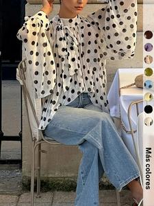 Esta blusa transparente con lunares es atemporal y chic, de cuello alto con lazada y mangas abullonadas.
