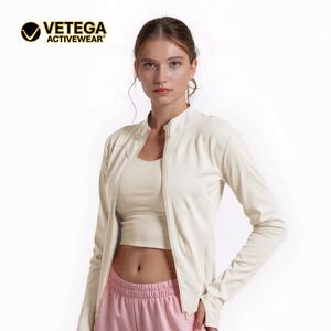 Chaqueta deportiva de manga larga para mujer de color claro con cremallera y orificios para los pulgares, adecuada para ropa deportiva de mujer en diversas ocasiones.