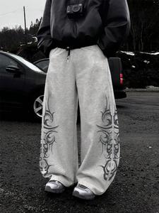Pantalones deportivos de corte holgado con estampado de calavera tribal, ideales para estilos millennial y gótico, cómodos para streetwear en todas las estaciones