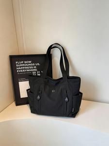 La bolsa tote ligera y espaciosa es ideal para uso diario. Es impermeable, sencilla, con interior compatible con laptops de 15 pulgadas, múltiples bolsillos laterales y una correa ajustable.