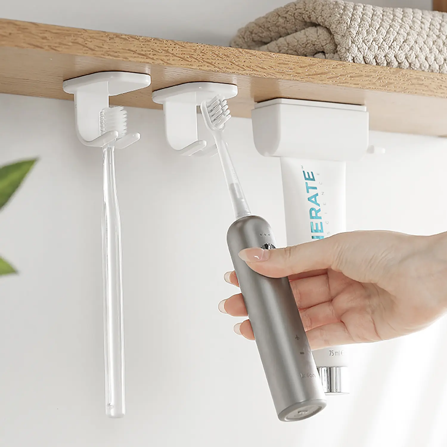 Toothbrush storage rack hanging at the bottom of the mirror cabinet. It's a punch-free adhesive wall-mounted simple storage rack, a white toothbrush rack.